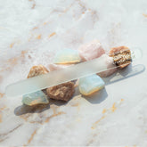 A single Nail Tek XL Crystal File 7 inch laid on top of decorative stones on marble background