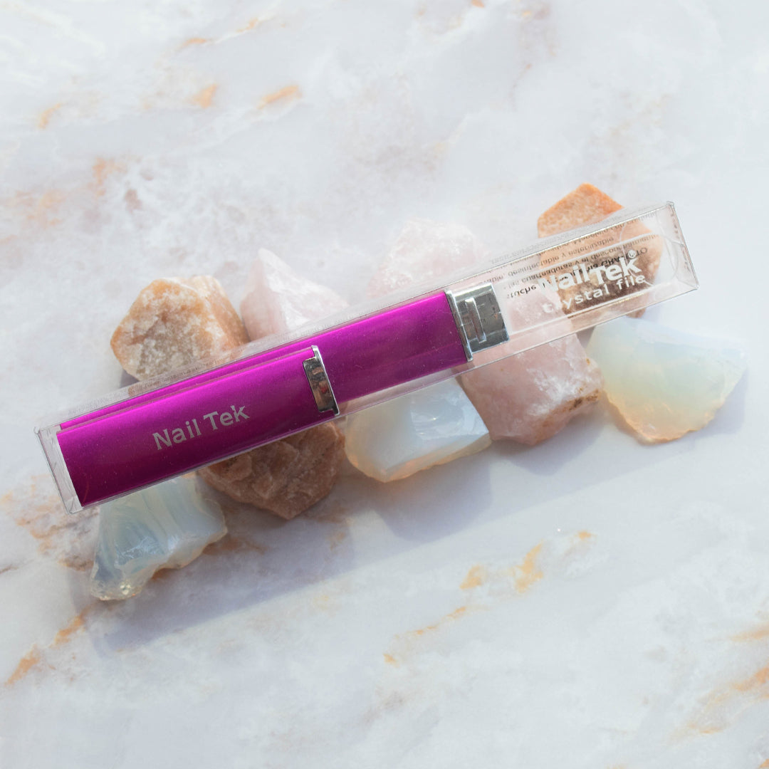 Packaged Nail Tek Medium 5 inch Crystal File with Fuschia Travel Case on top of decorative stones on marble background
